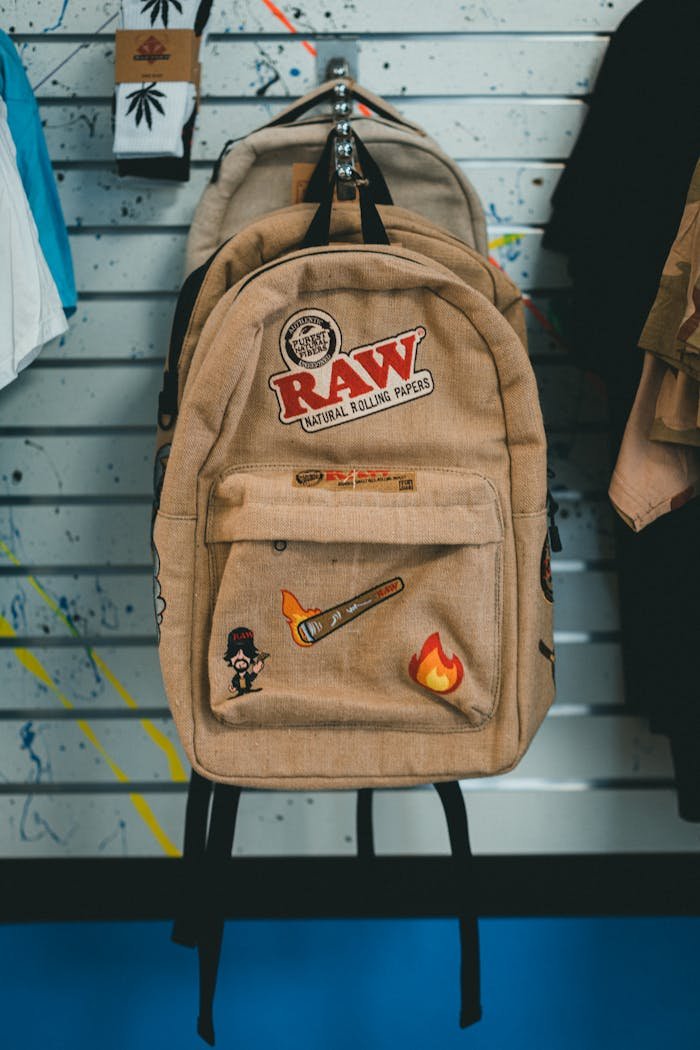 Beige backpack with artistic patches displayed in a store setting.