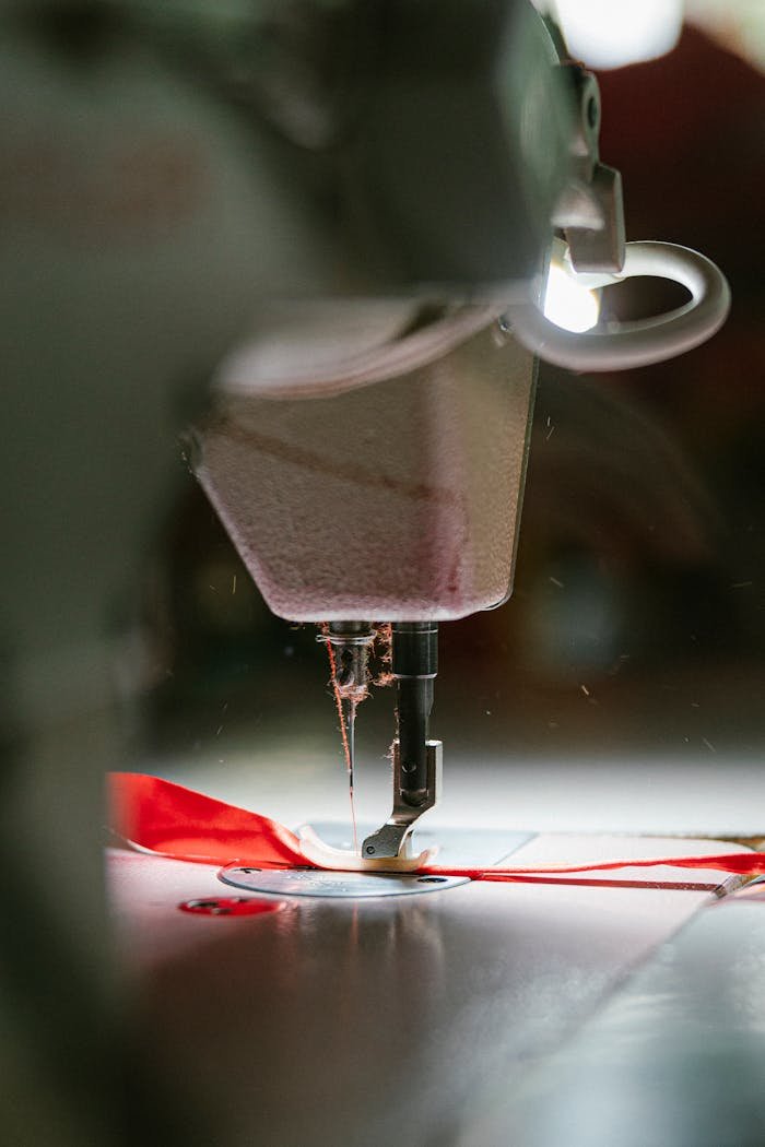 Detailed view of an industrial sewing machine working with red fabric, showing precision stitching.