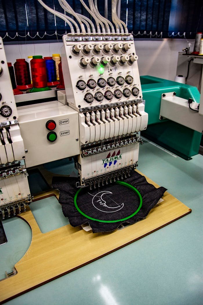about-us-01 High-quality embroidery machine stitching fabric in an industrial setting in Apucarana, Brazil.