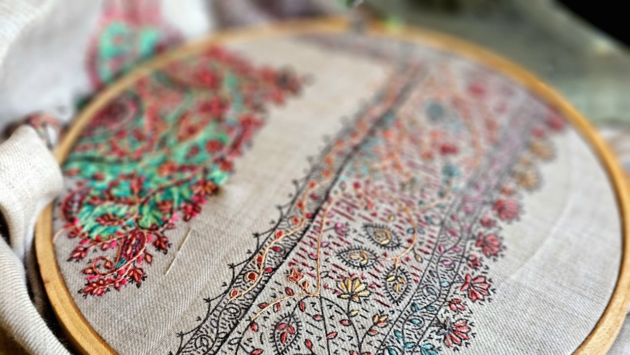 heros-img Colorful hand embroidery in progress on a fabric hoop, showcasing detailed craftsmanship.